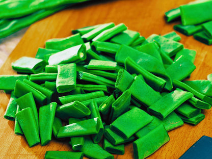 A pile of bright green, elongated vegetables on a wooden surface.