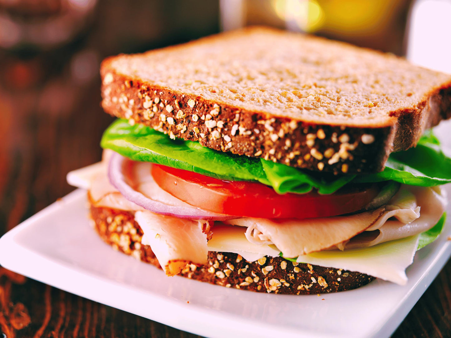 A close-up image of a sandwich on a white plate, featuring a variety of ingredients such as lettuce, tomato, and meat.