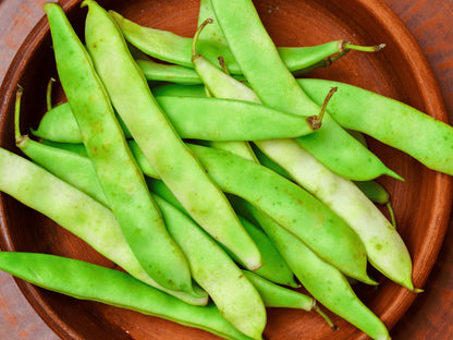 A wooden bowl filled with fresh green beans.
