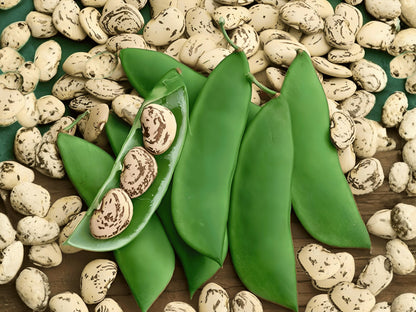 a variety of green beans and beans scattered on a wooden surface.