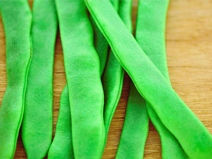 A close-up image of green beans on a wooden surface.